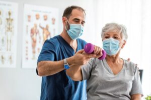 doctor helping an old woman to lift dumbell